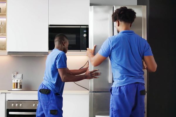 Two men installing a refrigerator Two men installing a refrigerator